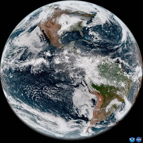 Image showing the round Earth with North and South America visible, there are loads of white wispy clouds covering the landmasses.