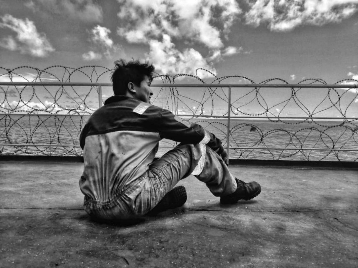 A seafarer on deck looks out to sea