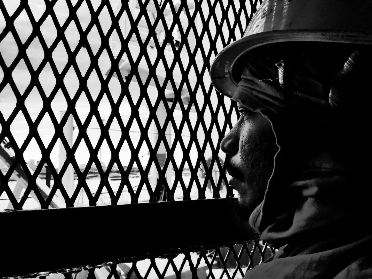 A seafarer behind a grill stares out to sea