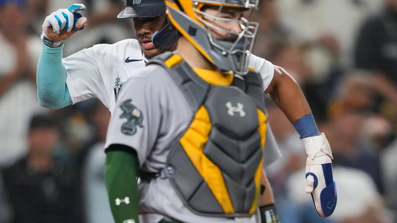 Seattle Mariners' Julio Rodriguez scores as Oakland Athletics catcher Shea Langeliers stands...