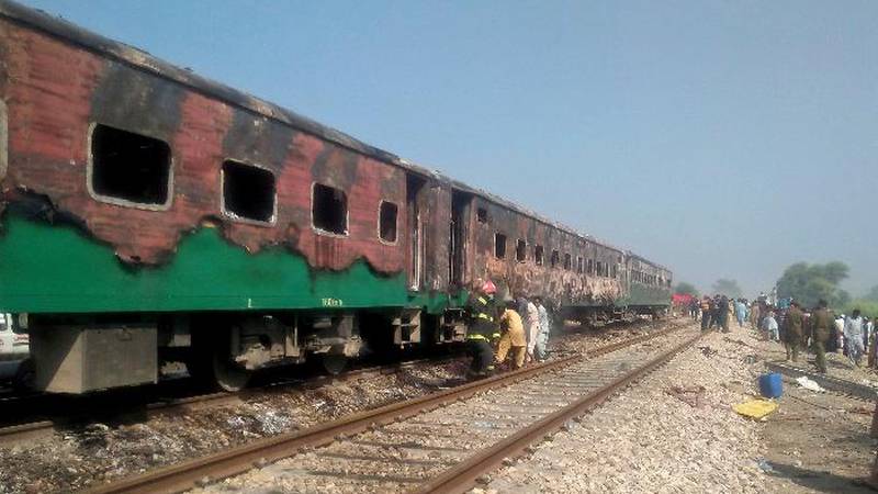 Pakistani officials examine a train damaged by a fire in Liaquatpur, Pakistan, Thursday, Oct....