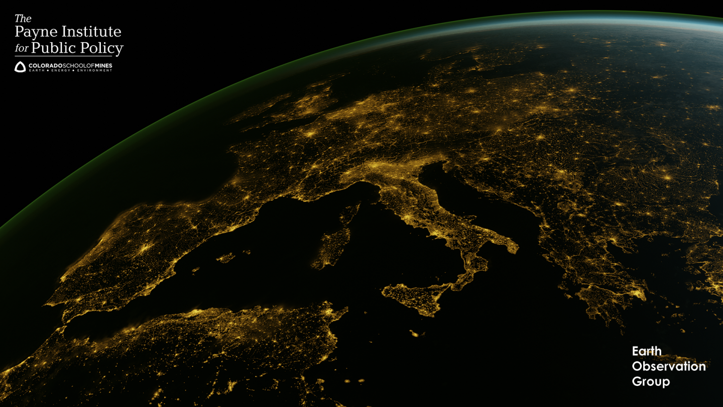 Satellite imagery at night time of Earth over Italy looking diagonally, with the curve of the Earth in the top of the image. The landmasses are lit up in golden where lights are on